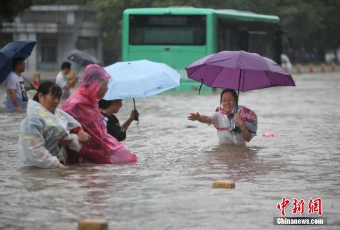 7月20日，鄭州遭遇強降雨，在經(jīng)三路、農(nóng)業(yè)路上，市民互相幫助走在齊腰深的積水里。 圖片來源：視覺中國